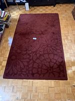 Top-down view of the burgundy wool rug showing floral pattern and condition.