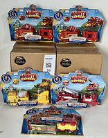 Four Mighty Express motorized toy trains sealed in original packaging (Rescue Red, Build-it Brock, and Freight Nate). Two Spin Master boxes visible underneath.