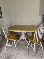 Full view of oval wood kitchen table with 4 chairs set in a room with tiled floor