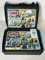 Two vintage Star Wars Empire Strikes Back collectors figure carry cases, front side showing artwork featuring characters and scenes from the movie, sitting side by side with one case on top of the other.