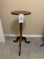 Front view of the traditional brown wood pedestal table showing round top and tripod base
