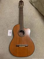 Full view of the classical guitar showing the body and strings on carpet surface.