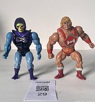 Front view of Skeletor and He-Man vintage action figures with product tag