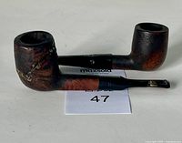 Two vintage wooden tobacco pipes, both with visible damages including chipped mouthpiece and worn surface.