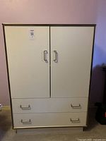 Front view of white cabinet with two doors on top and two drawers below, metal handles visible.