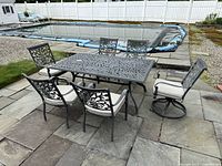 Full view of cast aluminum dining table with six chairs arranged on patio