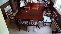 Cherry finish rectangular dining table with four side chairs and two head chairs arranged around it.