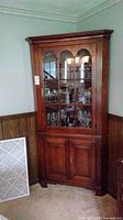Front view of the full mahogany corner hutch showing upper glass display cabinet with arched mullion doors and lower wood cabinet