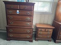 Photo showing full view of the dresser and nightstand with natural light from window highlighting the wood finish and brass handles