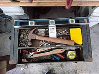 Top view of open drawer with hammer, nails, screws, wire brush, crimping tool, level, measuring tape, and yellow tool case