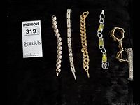 Overview of lot showing six assorted bracelets on black background with auction tag
