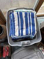 Folded pool towels with blue and white stripes on top in a plastic bin