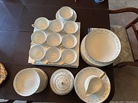 Top view of set showing multiple teacups arranged on saucers, with multiple stacked plates and serving pieces including sugar bowl and creamer.