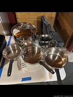 All cookware set displayed on table, includes large stock pot with lid and three saucepans