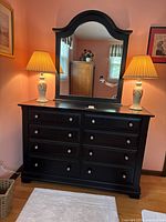 Full view of the dark walnut dresser with large arched mirror and two matching ceramic table lamps with floral designs and fabric lampshades.