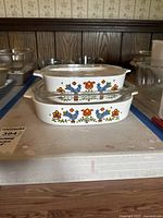 Two vintage Corning Ware casserole dishes with Country Festival pattern stacked on each other.