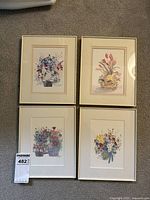 Four framed flower watercolor prints laid out on carpet showing color and frame style.