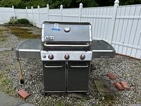 Front view of closed Weber Genesis grill on gravel