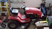 Side view of red Yard Machines ride-on mower with black seat and steering wheel