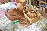 Five woven baskets arranged on a floral tablecloth, showing variety in shape and weave style.
