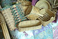 Various handwoven baskets arranged on a patterned quilt surface showing shapes, weaving patterns, and decorative elements for the lot