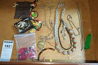 Multiple costume jewelry items laid out including necklaces, bracelets, earrings, loose beads, and a pin brooch.