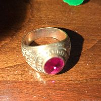 Gold-tone ring with ornate scrolling and pink oval cabochon