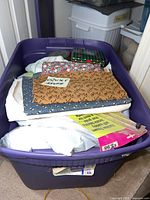 Wide shot of purple bin packed with multiple folded fabric pieces, tin box and packaged notions.