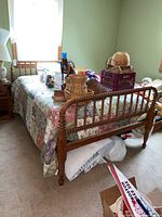 Vintage wooden spool bed with bedspread in a bedroom, showing overall condition and size.