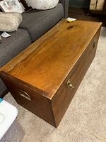 Top side view of rectangular wooden storage chest showing brass handles and natural wood finish