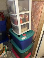 Photo showing white three-drawer plastic organizer chest containing yarn and stacked on top of three large plastic storage bins in blue, green, pink, and gray colors.