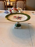 Front view of the Limoges pedestal plate showing floral design and green with gold detailed rim.