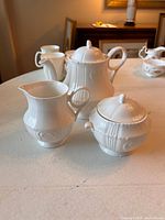 Photo of Royal Grafton fine bone china 3 piece tea set on table, showing teapot, milk jug and sugar bowl from the front angle.