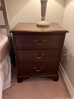 Front view of the vintage 3 drawer side table showing surface wear on top and three drawers with brass handles.