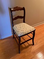 Full view of vintage ladder back chair showing wooden frame and floral cushioned seat