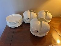 Overview of stacked 12 white side plates and grouped cups and saucers showing lot quantity.
