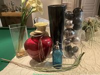 Photo showing five vases of various shapes and colors along with a vintage blue glass soda siphon bottle.