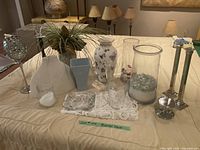 Wide shot of all decorative items on table including vases, candle holders, and decorative glasses.