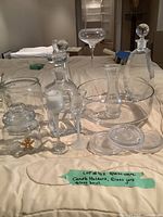 Photo showing entire assortment including glass bowls, decanters with lids, glass coasters, and canisters arranged on a table