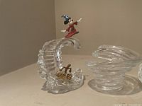 Photo showing three Fantasia collection glass decor pieces with Mickey Mouse figures and a clear swirl bowl.