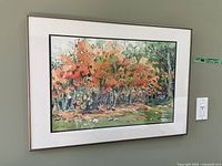 Frontal view of the framed watercolour painting of autumn trees hanging on a wall, showing overall artwork and frame.