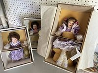 Three Franklin heirloom dolls still in original packaging, never removed, showing varying sizes and outfits.