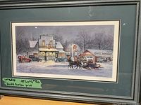 Framed Harold Burton print showing a winter scene with horse-drawn sleigh, vintage cars, and buildings, in blue-gray frame and green matting.