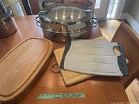 Roasting pan, several wooden cutting boards and a plastic cutting board arranged on a table.