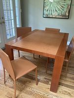 Rectangular wooden dining table with four leather-wrapped chairs around it, showing overall set and table surface.