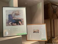 Two framed prints displayed on a shelf including the larger 'Sharing' print and a smaller framed print