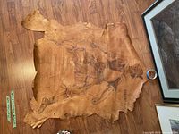 Full view of leather artwork laid out on floor showing person on horseback image and artist signature.