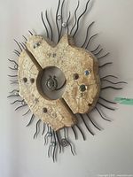 Front view of abstract wall art showing two cracked beige pieces with metal and glass accents on sunburst metal frame