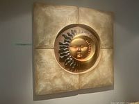 Full view of square wall art sculpture showing sun and moon face relief.