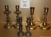 Photo showing three pairs of vintage solid brass candlesticks arranged in a row, largest at the back, smallest in front.